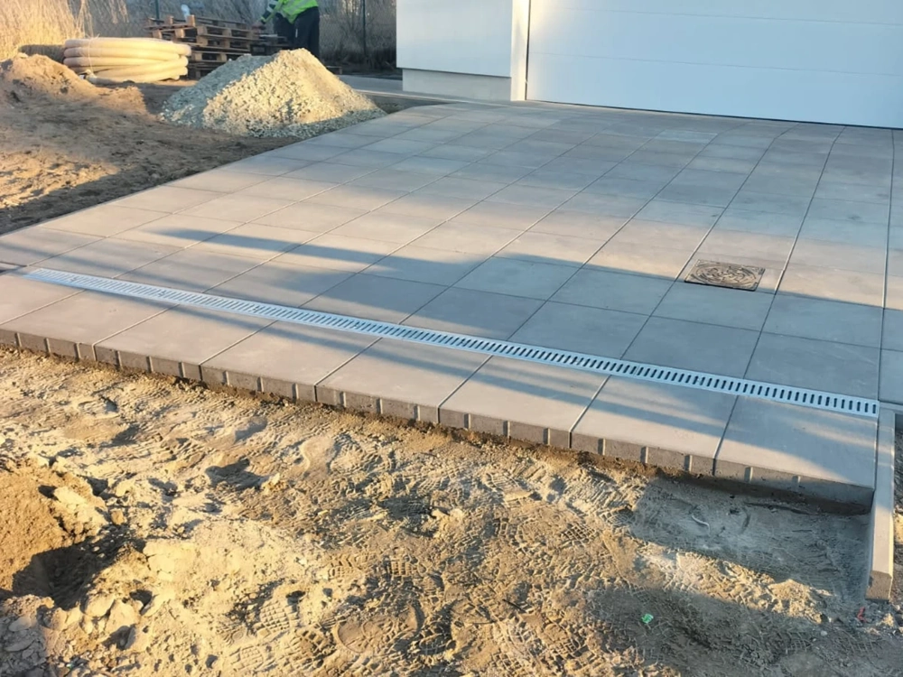 Układanie kostki brukowej na podjeździe z liniowym odwodnieniem
