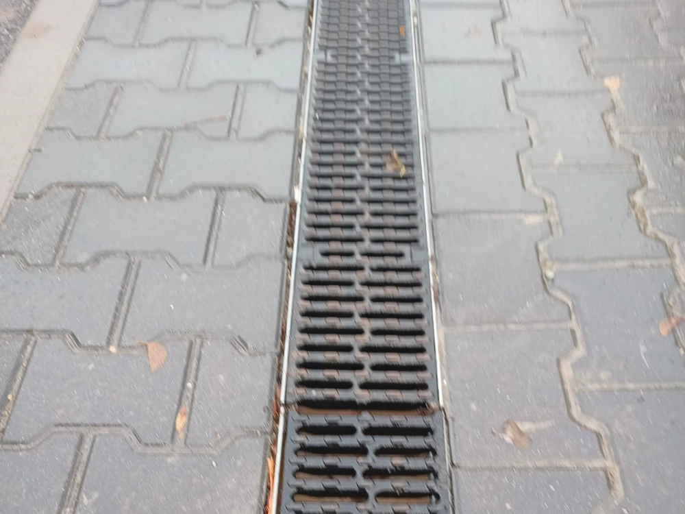 Odwodnienie liniowe z metalową kratką osadzone w kostce brukowej chodnika