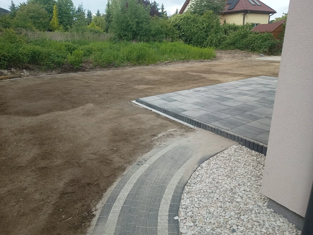 Opaska wokół domu z kostki na tle wyrównanego terenu