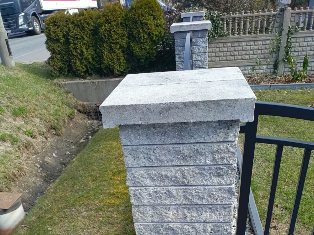 Pionowy słupek ogrodzenia z bloczków betonowych z daszkiem i przęsłem metalowym