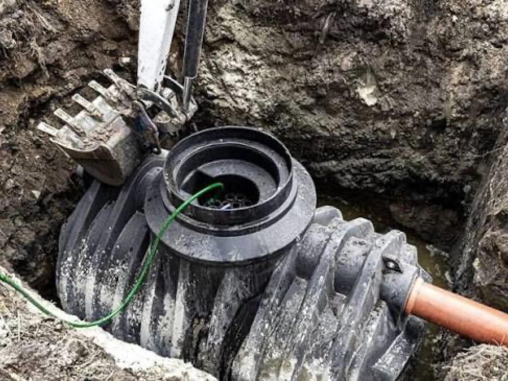 Montaż szamba ekologicznego – czarny zbiornik w wykopie z podłączonymi rurami