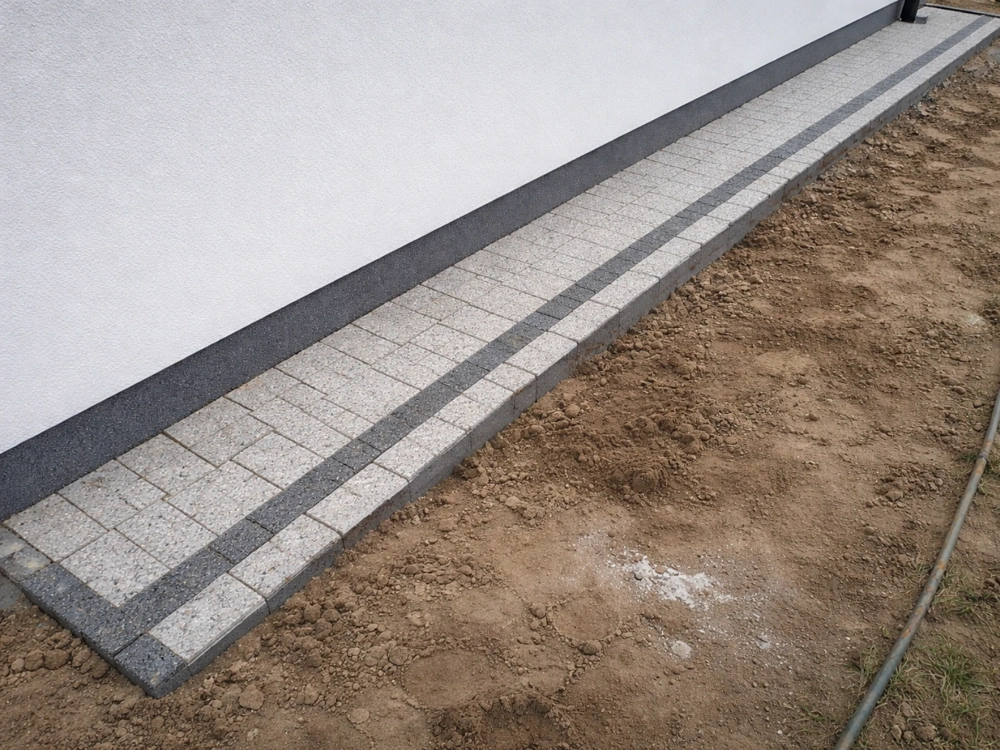 Opaska wokół domu z kostki w odcieniach szarości przy białej elewacji